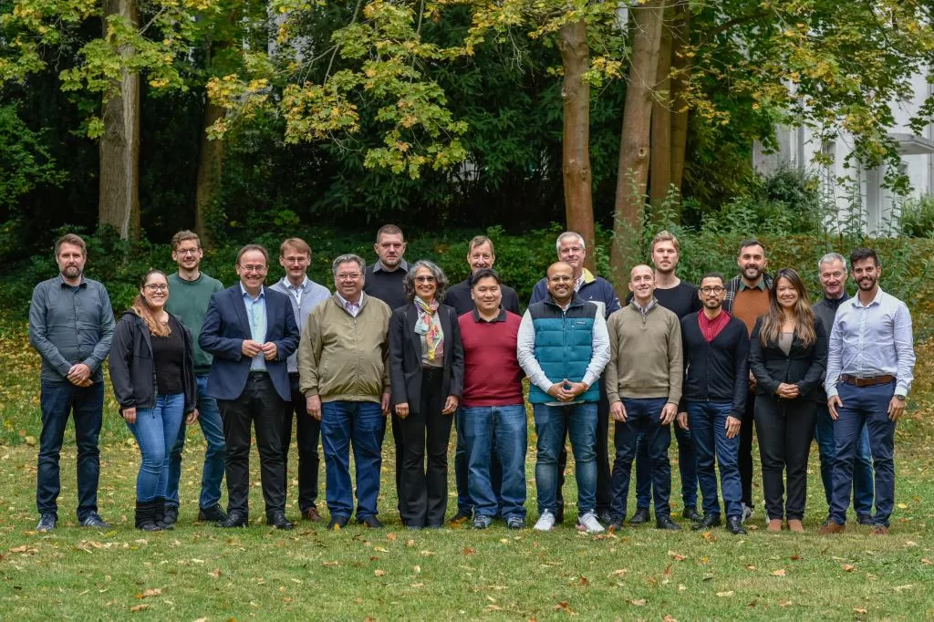 Foto de grupo ao ar livre com cerca de 20 participantes em duas fileiras, árvores com folhas de outono ao fundo; registro do workshop de aquicultura sustentável em Berlim.