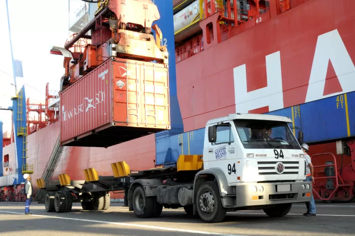 Caminhão realiza operação de carregamento de contêiner no Porto de Santos