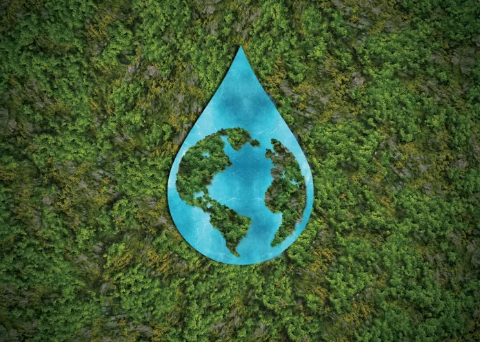 Gota de água com formato do planeta Terra sobre uma floresta, simbolizando sustentabilidade ambiental.