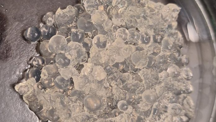 Esferas de hidrogel transparentes e úmidas acumuladas em um recipiente.