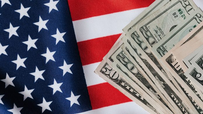 Cédulas de dólar americano dispostas sobre a bandeira dos Estados Unidos, representando o comércio exterior e acordos tarifários.