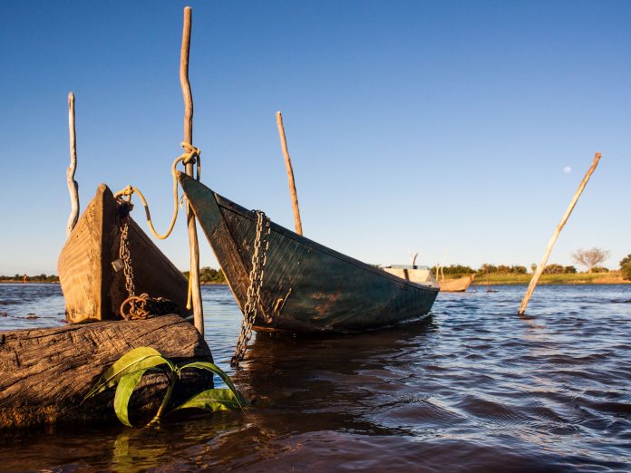 Estruturas de cultivo aquícola ou embarcações pesqueiras artesanais em ambiente de rio.