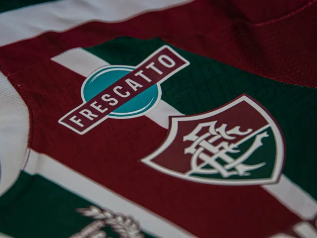 Detalhe da camisa de futebol grená e verde do Fluminense com patrocínio da Frescatto visível.